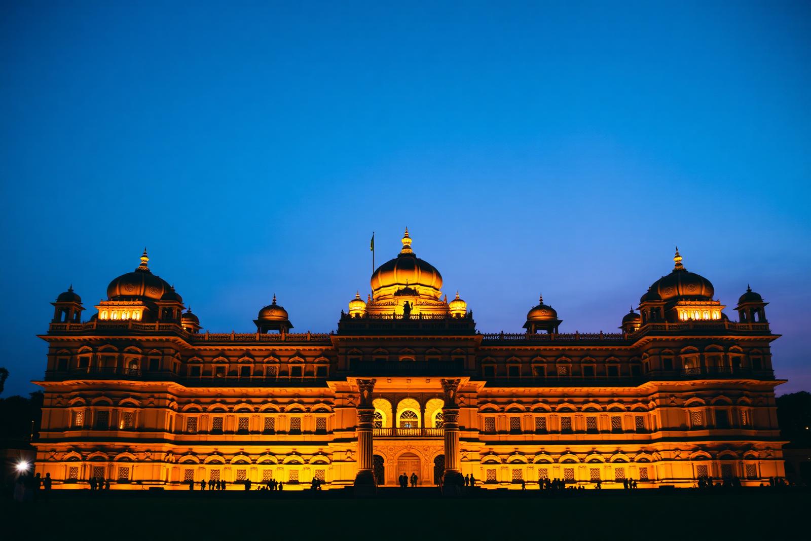 Mysore Palace illuminated at dusk against a deep blue sky