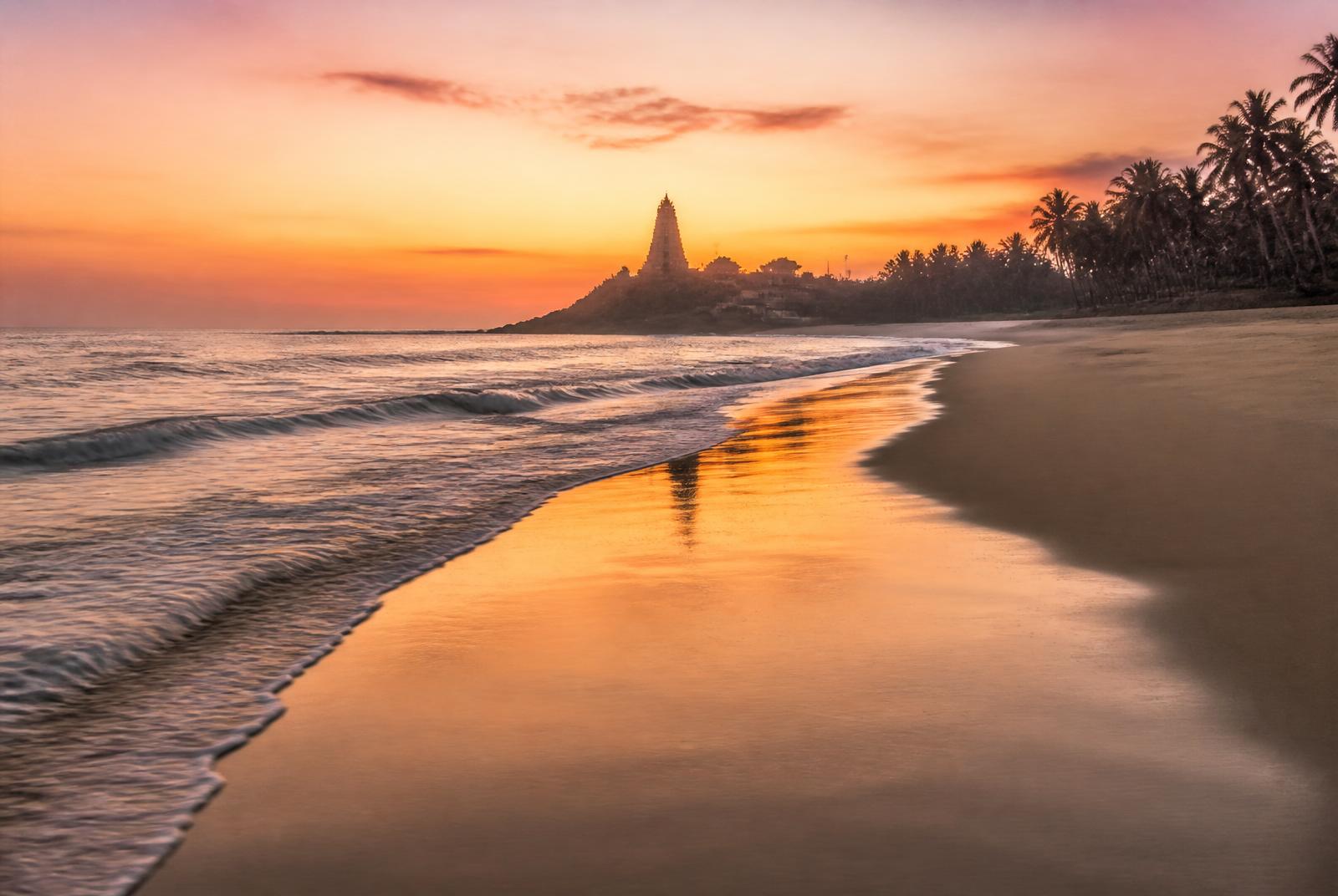 Serene Murudeshwara Beach at sunrise with gentle waves and temple silhouette