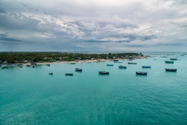 Small fishing boats anchored in a calm turquoise coastal bay