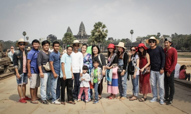 A large travel group posing together in front of a grand ancient temple complex