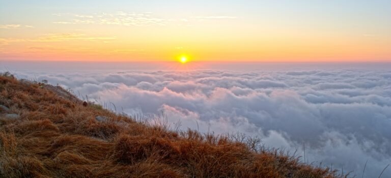 Sunrise viewed from a hilltop above a rolling sea of clouds