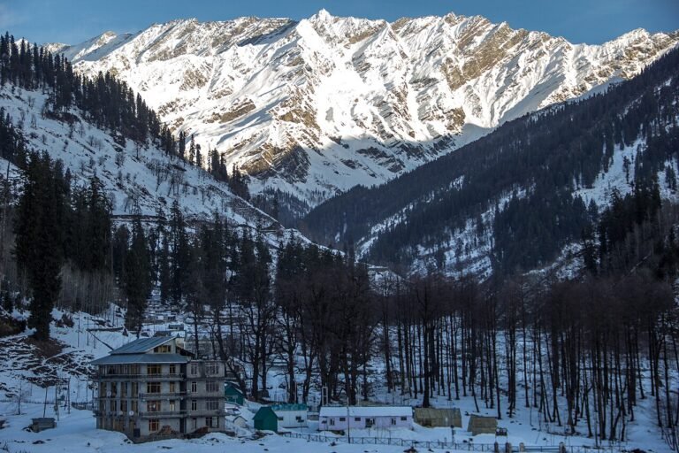 Snow-capped mountain peaks rising above a village in a green valley